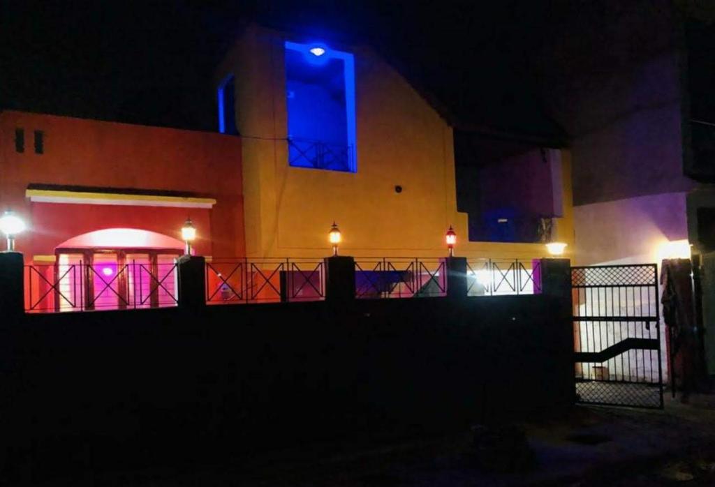 um edifício à noite com luzes roxas e azuis em Vamoose Paradise em Mahārājpur