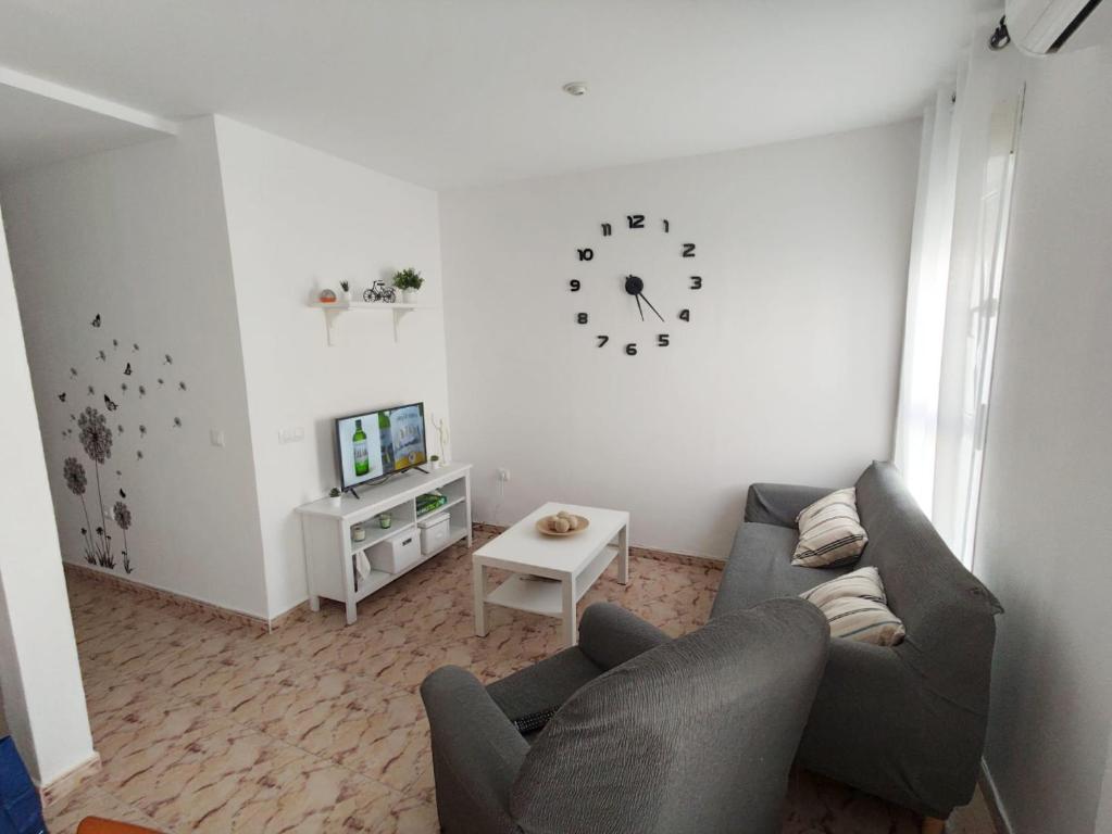 sala de estar con sofá y reloj en la pared en Apartamento Conil Zona tranquila con fácil aparcamiento, en Conil de la Frontera