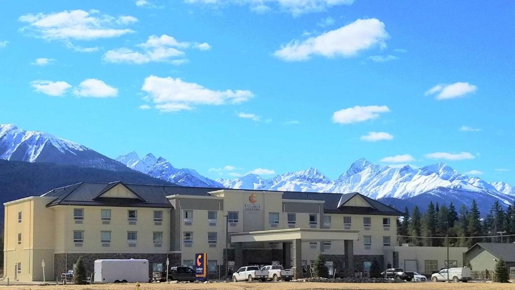un grand bâtiment avec des montagnes en arrière-plan dans l'établissement Comfort Inn & Suites, à Valemount