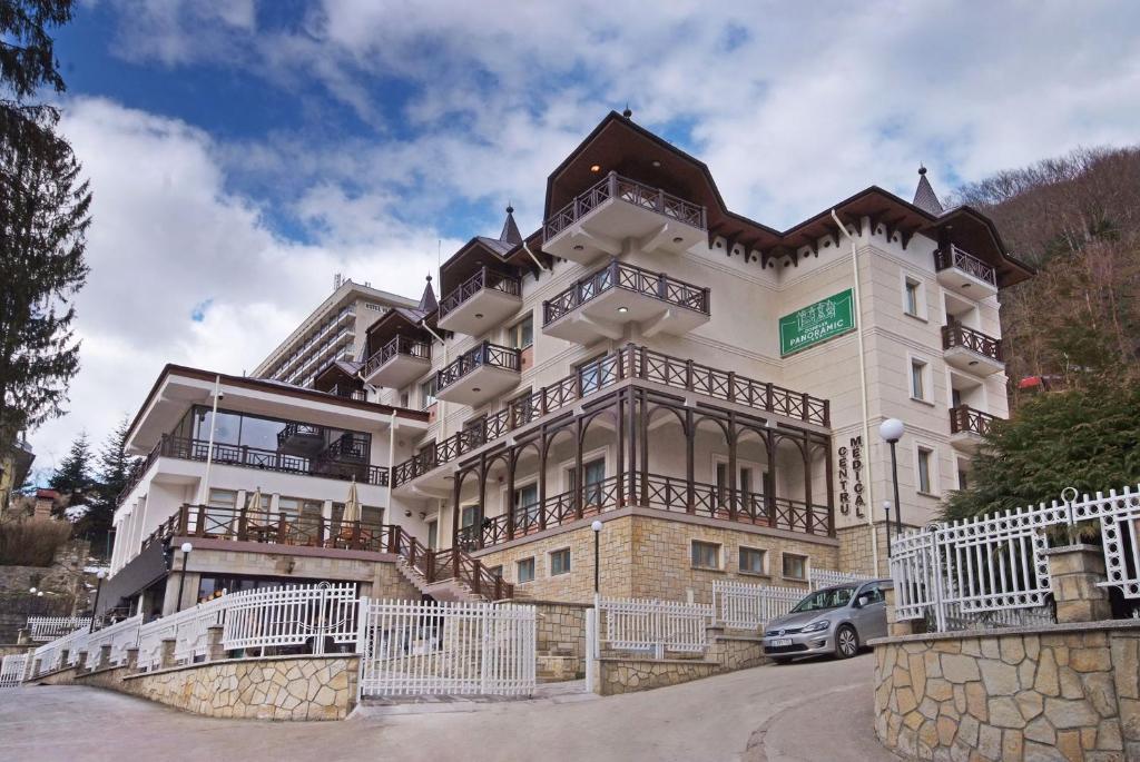 un gran edificio con un coche aparcado delante de él en COMPLEX PANORAMIC en Slănic-Moldova