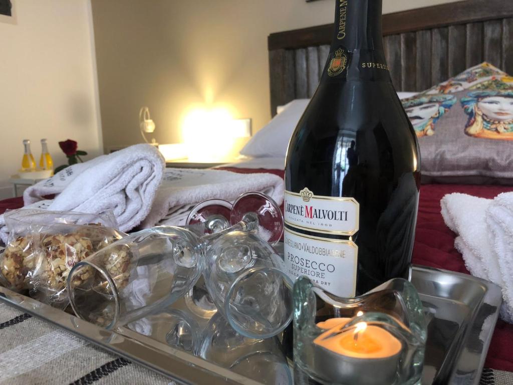 uma garrafa de vinho e uma bandeja com copos e uma vela em b&b nonno peppe em Palermo