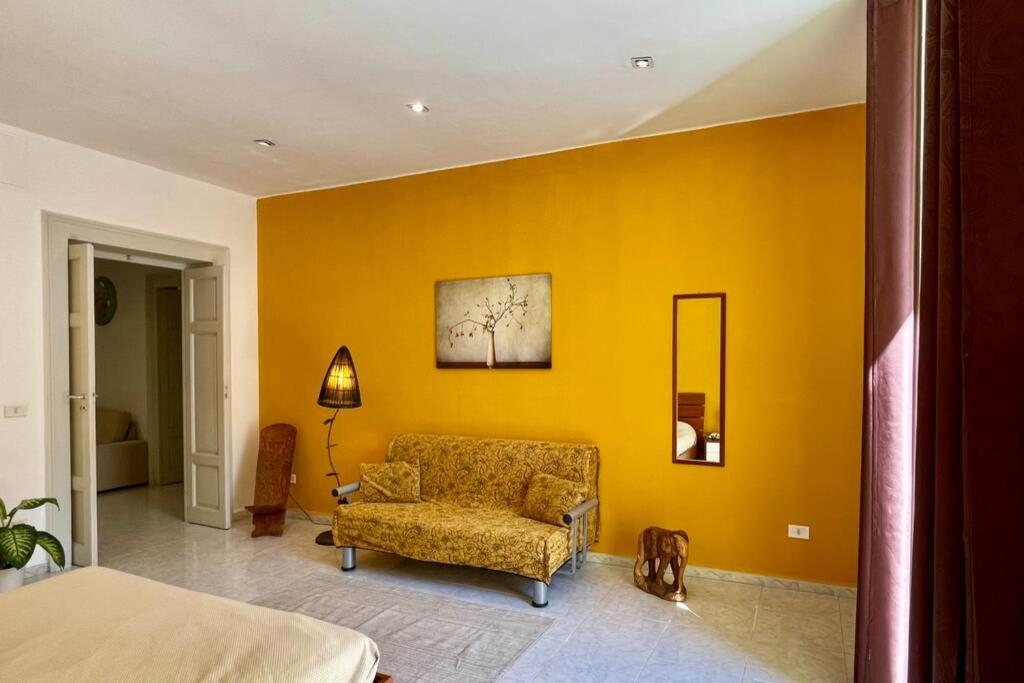 a bedroom with a couch and a yellow wall at PetinoInApulia - Appartamento per famiglie e amici in Bari