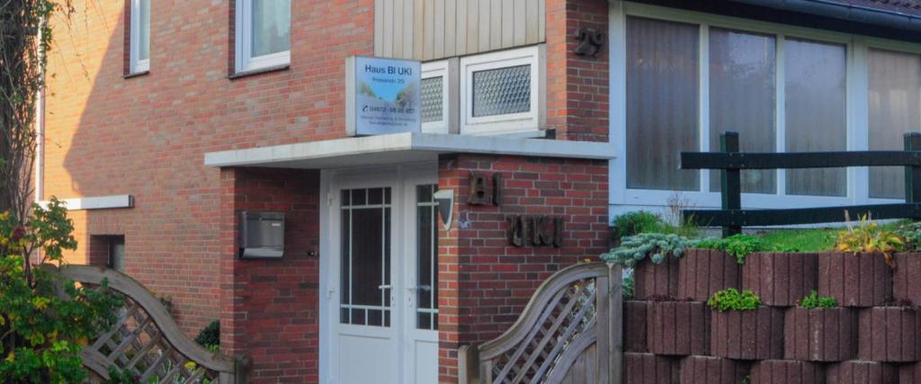 una casa de ladrillo con una puerta blanca y una valla en Bi Uki, en Langeoog