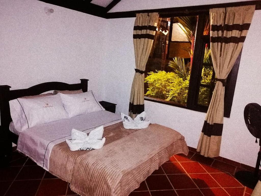 a bedroom with a bed with two white towels on it at LoMar Sol&Luna in Sasaima
