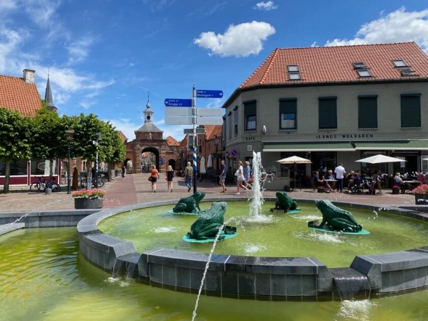 una fuente en una plaza de la ciudad con gente caminando por ahí en 's Lands Welvaren en Aardenburg