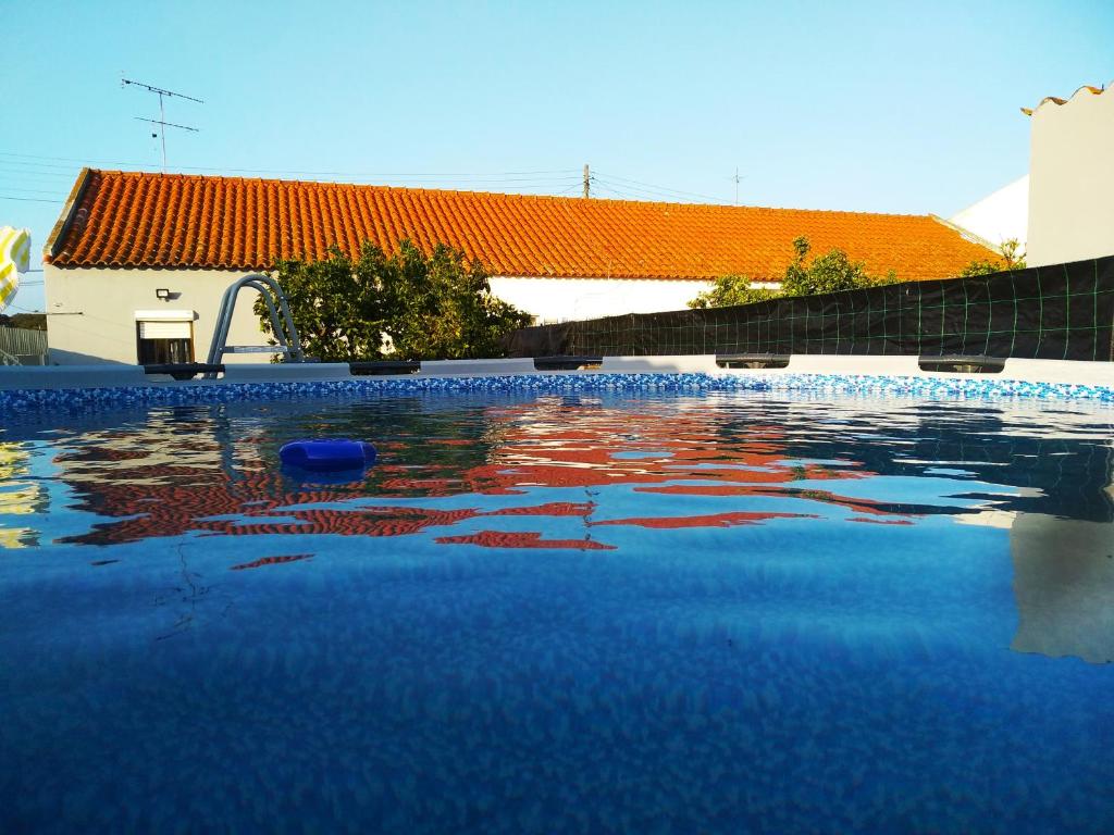 a swimming pool with blue water in front of a building at Cantinho do Sol in Grândola