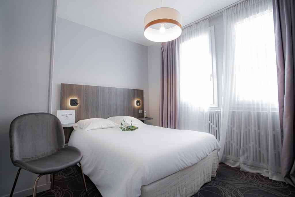 um quarto com uma cama branca e uma cadeira em Hôtel Central em Poitiers