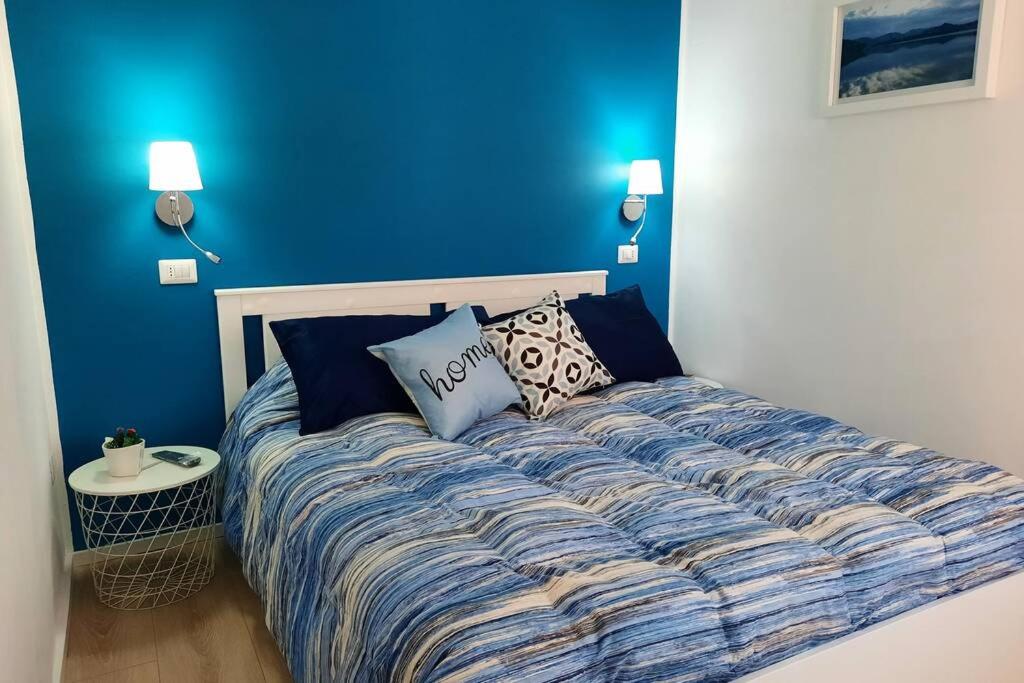 Bett in einem Zimmer mit blauer Wand in der Unterkunft Meli's House in Vibo Valentia