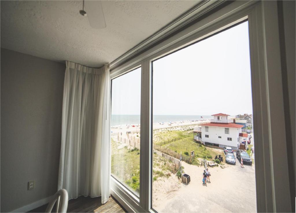 a room with a window with a view of the beach at Surf Club Oceanfront Hotel in Dewey Beach