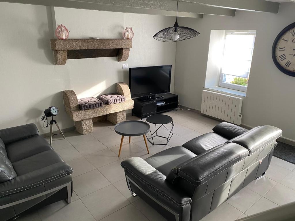 a living room with a couch and a tv at La Petite Maison in Saint-Nicolas-du-Pélem