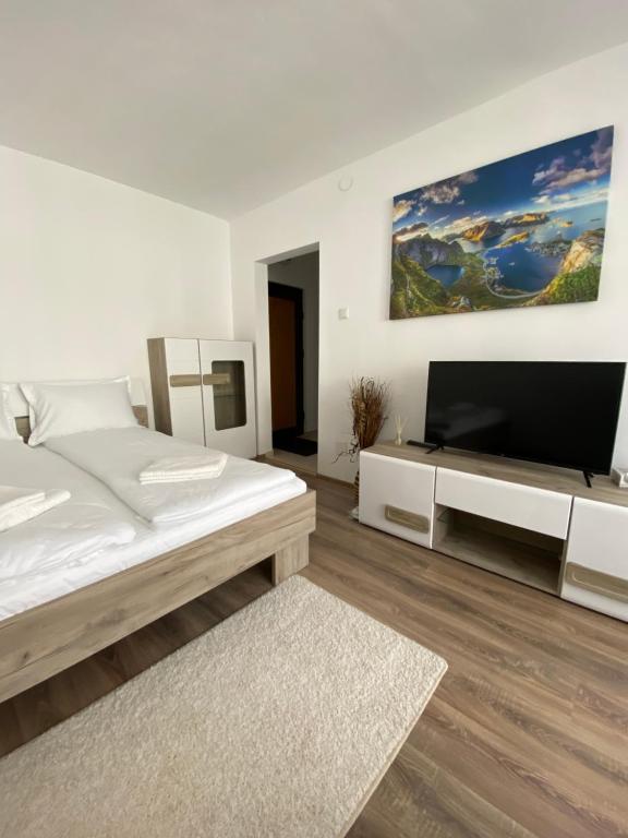 una camera bianca con un grande letto e una TV a schermo piatto di Focus Home Next a Miercurea-Ciuc
