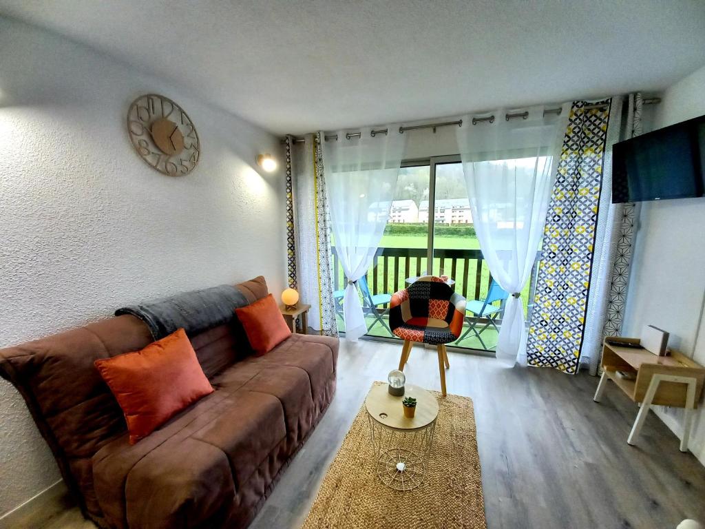 a living room with a brown couch and a window at Appartement Cabine St-Lary-Soulan, Calme, Entièrement Rénové in Saint-Lary-Soulan