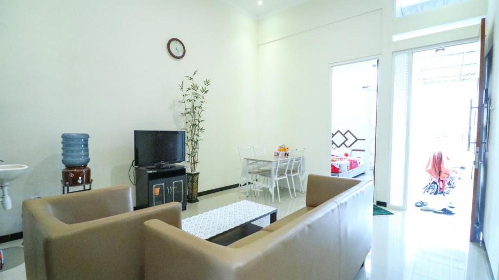 a living room with a couch and a tv and a table at Villa Harmoni Syariah by Masterpiece Villa in Karangploso