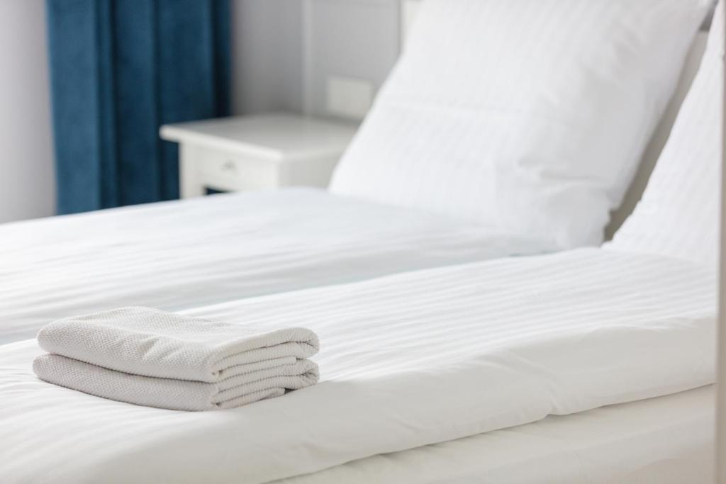 a stack of towels on a white bed at Baltic Apartments Seaside Residence in Gdańsk