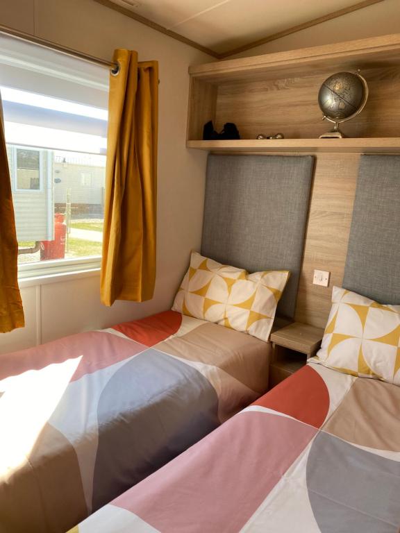 two beds in a small room with a window at Beachfront Lodge, Lossiemouth Bay in Lossiemouth