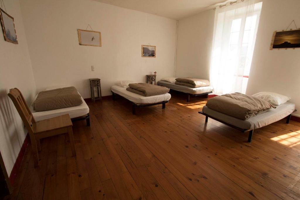 three beds in a room with a wooden floor at Gite d&#39;étape Les Diligences in Roquefixade