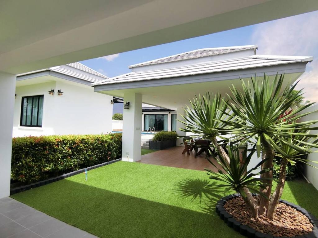 a house with a yard with grass and palm trees at Lux9 Private Pool Villa HuaHin in Hua Hin