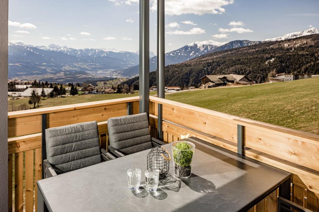 a table and chairs on a balcony with mountains at Sweet Dolomiti Sonneck in Maranza