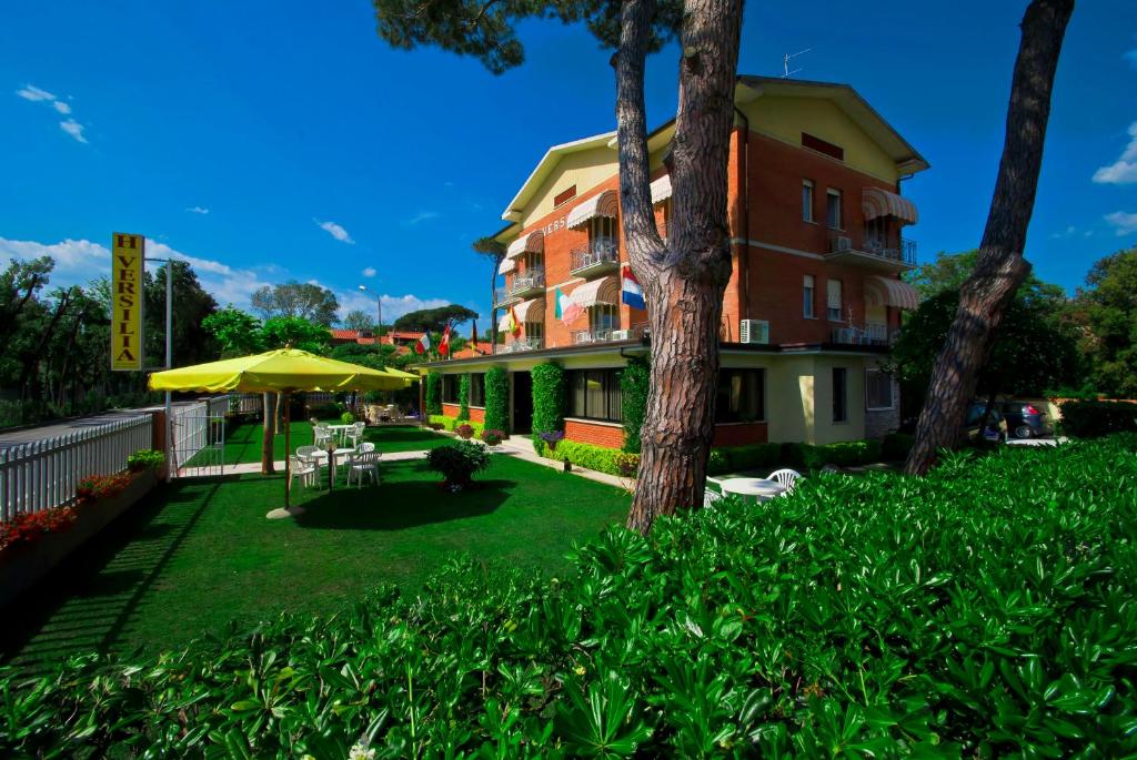 a building with an umbrella and a yard with grass at Hotel Versilia in Lido di Camaiore
