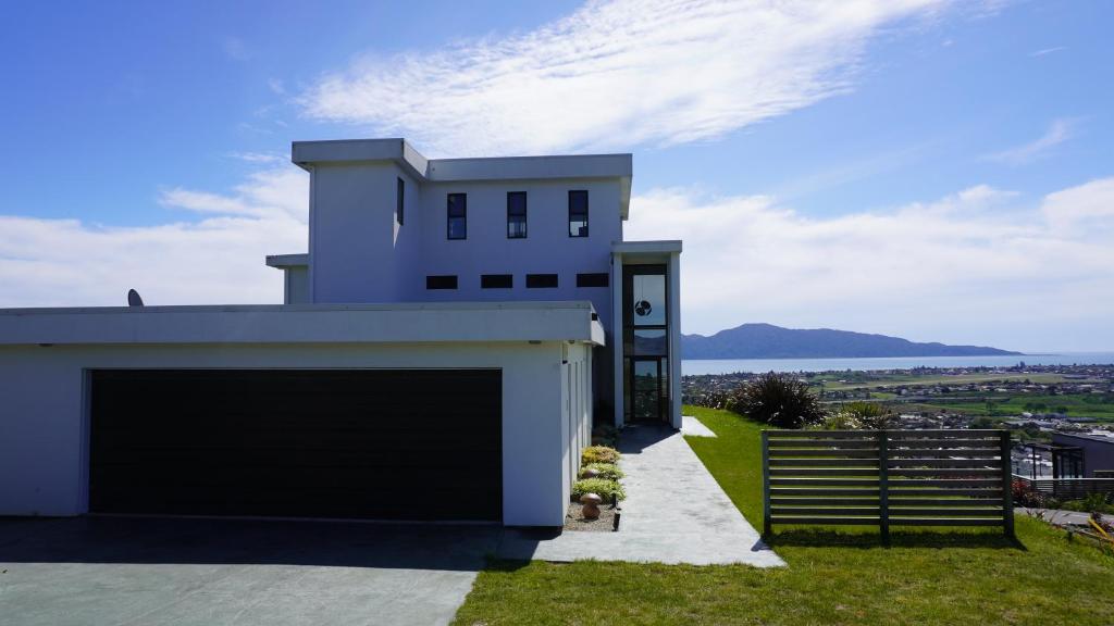 a white house with a garage on a hill at White House in Paraparaumu