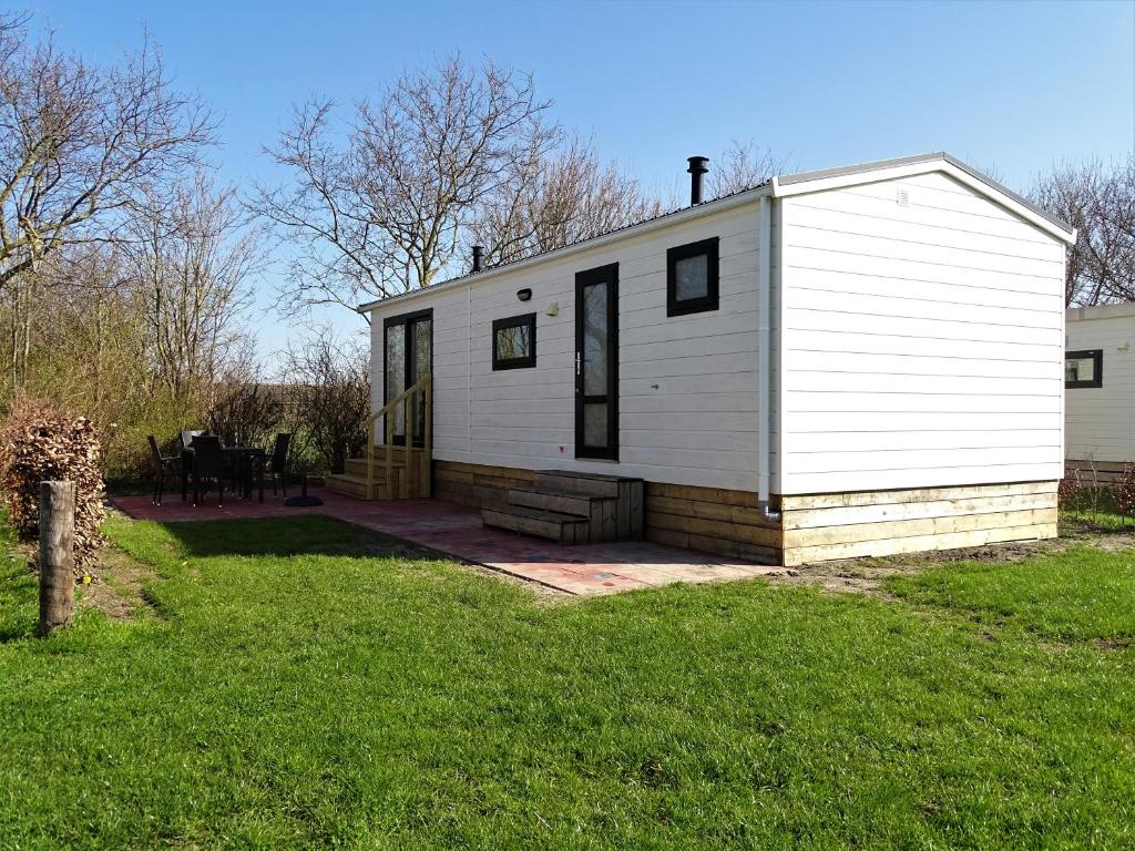 a small white house with a grass yard at Chalet 3 in Meliskerke