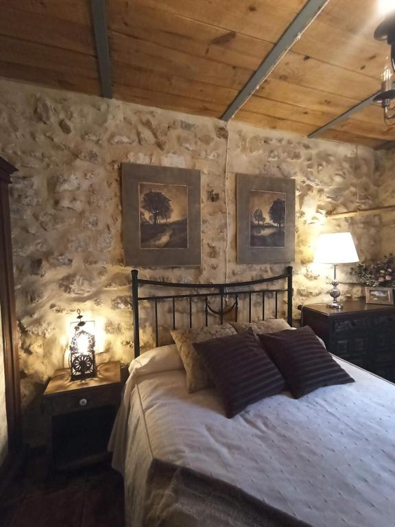 - une chambre avec un lit et un mur en pierre dans l'établissement LA HUETA Bajo, à Orcera