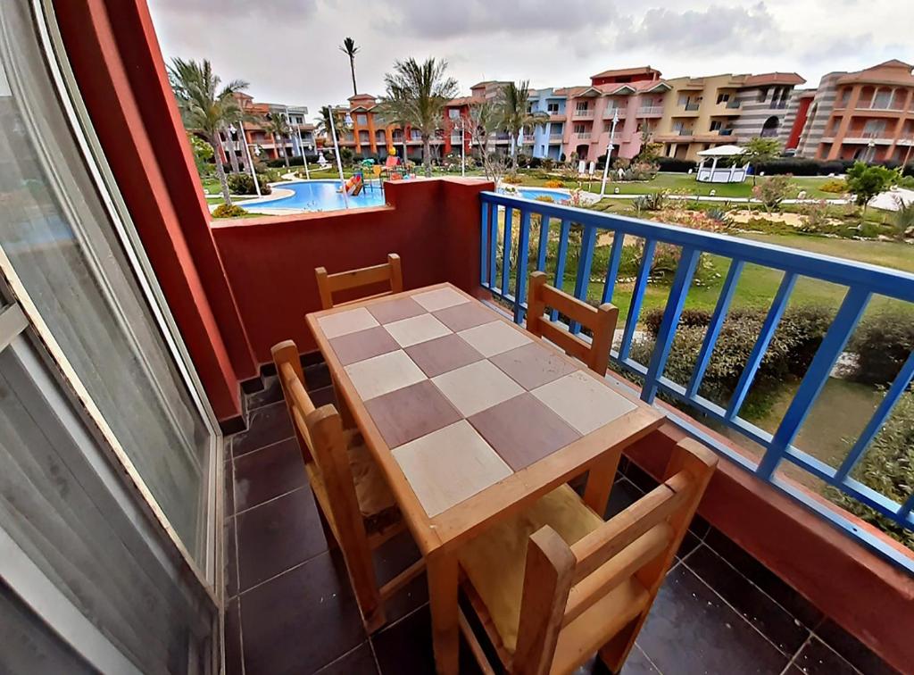 una mesa y sillas en un balcón con piscina en Porto Matruh - Your Family's Peaceful Summer Stay, en Marsa Matruh