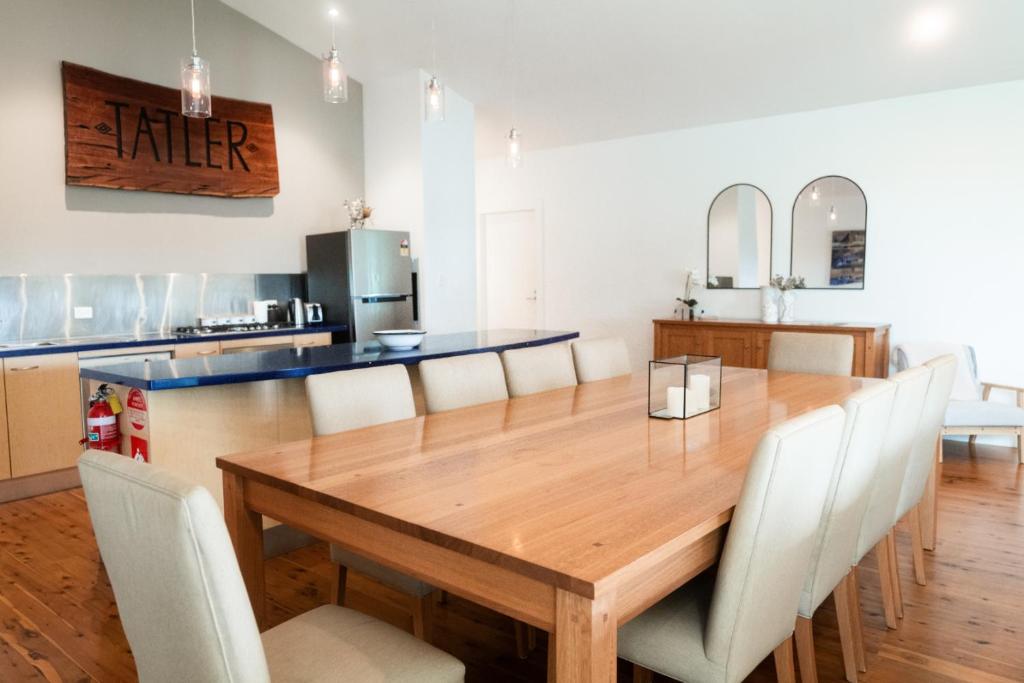 uma sala de jantar com uma mesa de madeira e cadeiras brancas em Idyllic Loft in the heart of Lovedale em Lovedale