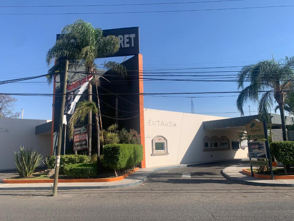 a building with a palm tree in front of a street at Motel Xcaret in Guadalajara