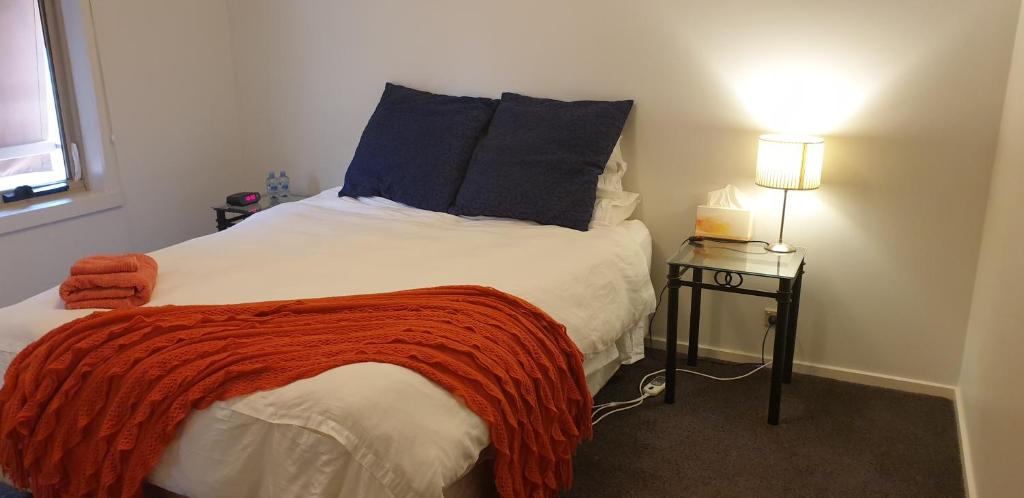 a bedroom with a bed with a red blanket on it at Quiet Room own Bathroom at home in Golden Square in Golden Square