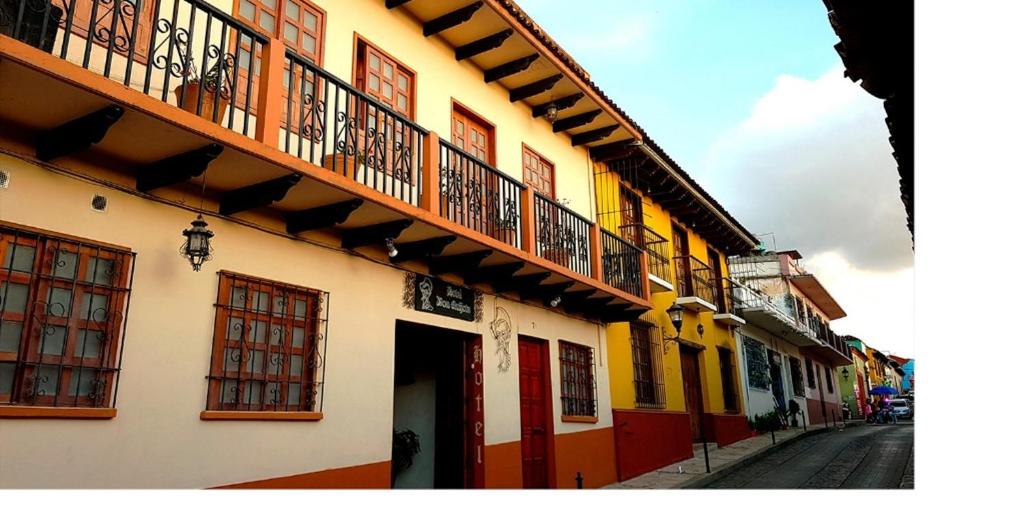 a row of buildings with balconies on a street at Hotel Don Quijote in San Cristóbal de Las Casas