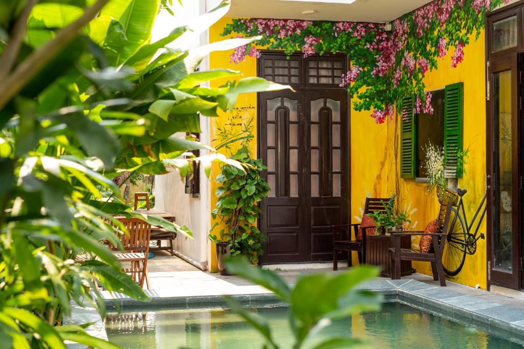 a house with a swimming pool and a house with yellow at Spring Garden Villa Hoi An in Hoi An