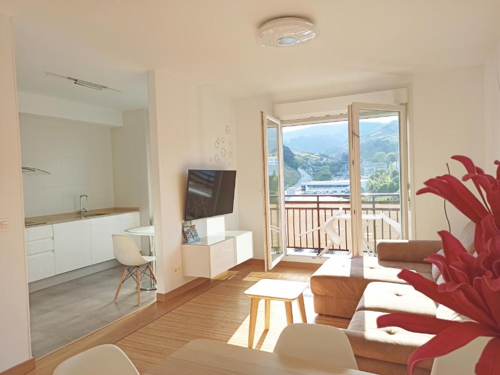 ein Wohnzimmer mit einem Sofa, einem TV und einem Balkon in der Unterkunft Apartamento PATXIKE con plaza de garaje in Bermeo