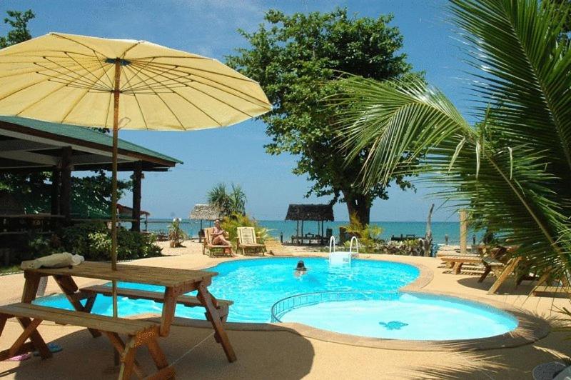 einen Pool mit einem Picknicktisch und einem Sonnenschirm in der Unterkunft Ocean View Resort in Ko Lanta