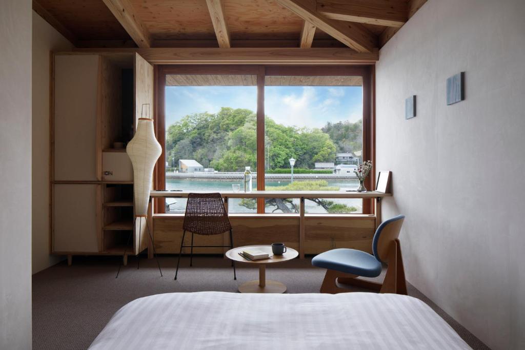 a bedroom with a bed and a large window at SOIL Setoda in Onomichi