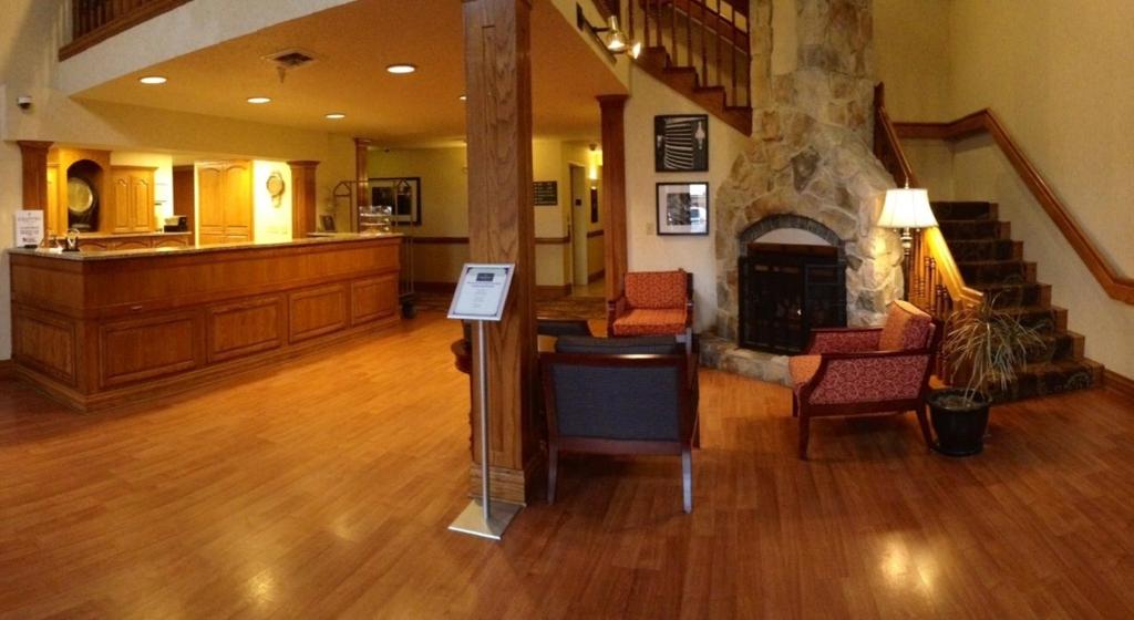 a living room with a fireplace and a stair case at Country Inn & Suites by Radisson, Lincoln North Hotel and Conference Center, NE in Lincoln