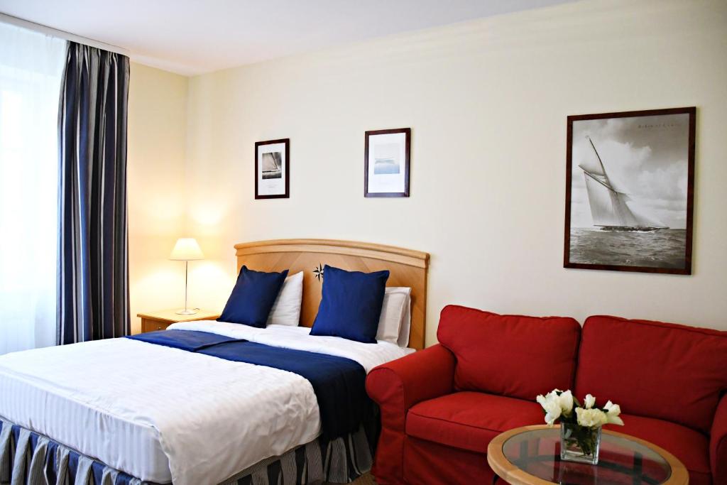 ein Hotelzimmer mit einem Bett und einem roten Sofa in der Unterkunft Žalias namas in Palanga