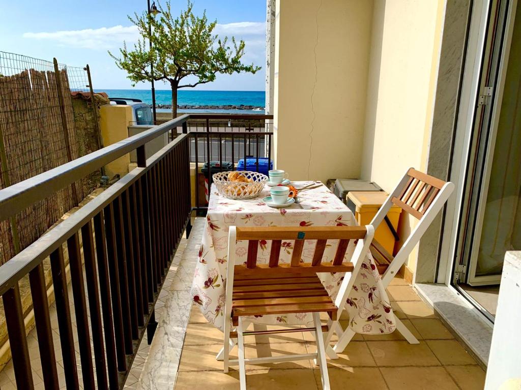 una mesa y sillas en un balcón con vistas al océano en La Posidonia sul mare, en Santo Stefano al Mare