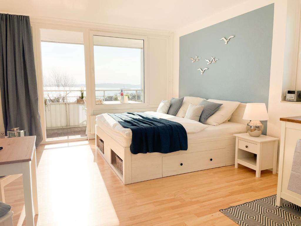 een slaapkamer met een bed en een groot raam bij Ferienwohnung mit Meerblick - Kiek ut in Eckernförde