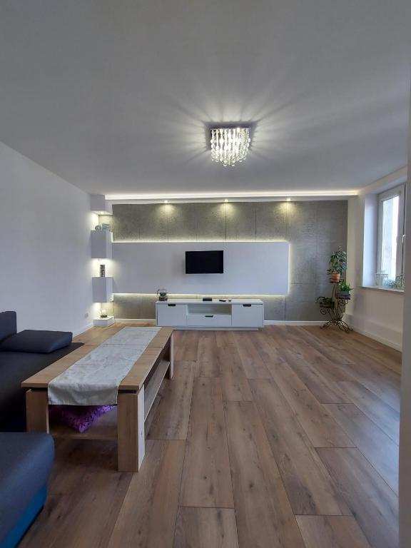 a living room with a table and a flat screen tv at Nowoczesny apartament w zacisznym sercu Torunia. in Toruń
