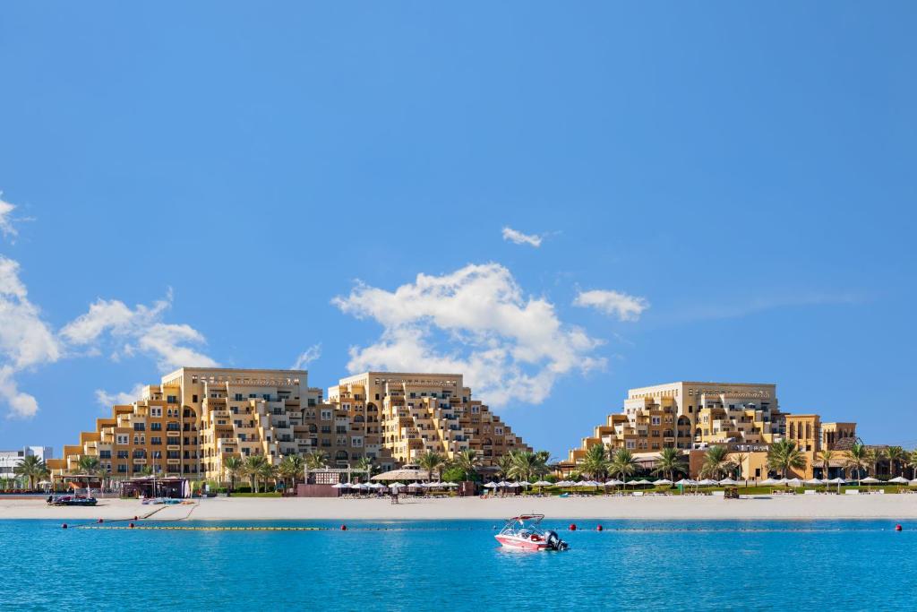 a boat in the water in front of buildings on a beach at Rixos Bab Al Bahr - Ultra All Inclusive in Ras al Khaimah