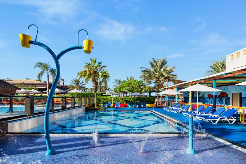 a pool at a resort with chairs and umbrellas at Rixos Bab Al Bahr - Ultra All Inclusive in Ras al Khaimah
