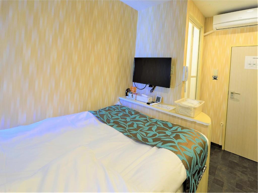 ein Hotelzimmer mit einem Bett und einem Flachbild-TV in der Unterkunft 西船橋駅前 HOTEL in Funabashi