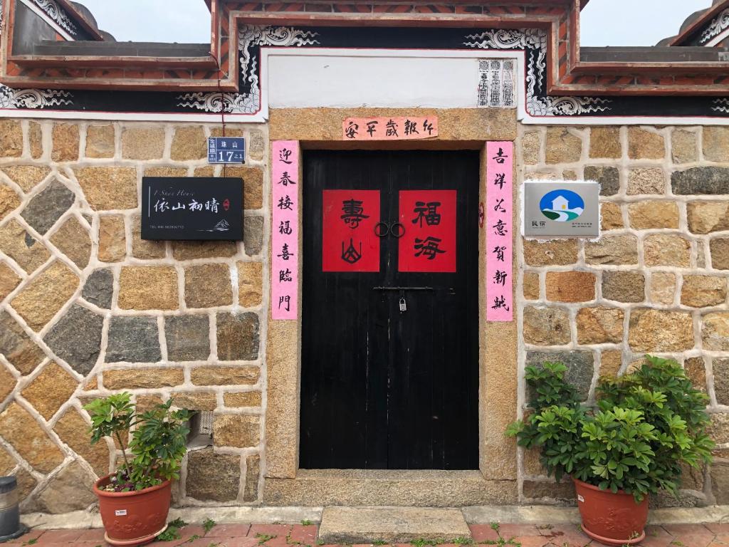 a black door in a stone building with plants in front at I-Shan House in Jincheng