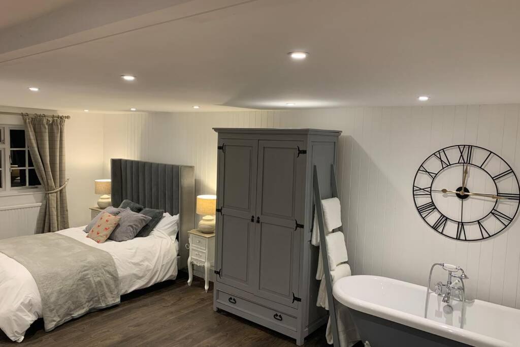 una camera con letto, vasca e orologio di Clock Cottage Self contained Rutland Rural Retreat a Manton