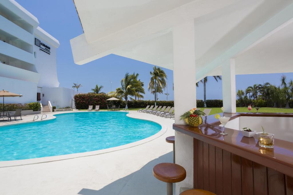 a swimming pool in a resort with chairs and a table at Gamma Campeche Malecon in Campeche