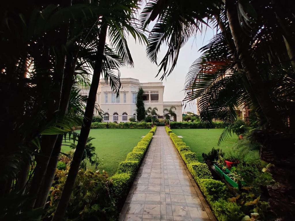 a view of a building from a garden with palm trees at Hotel Surya, Kaiser Palace in Varanasi