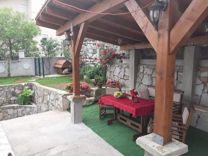 uma pérgola de madeira com uma mesa com uma toalha de mesa vermelha em Mini Garsonjera em Podgorica