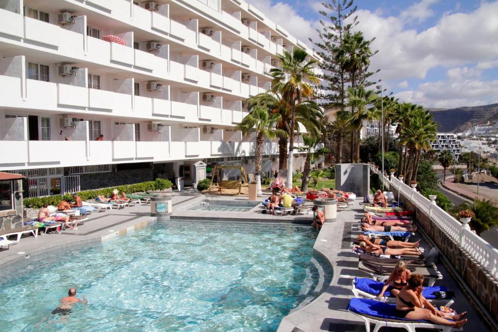 een groep mensen die in stoelen in een zwembad in een hotel zitten bij Aparthotel Maracaibo in Puerto Rico de Gran Canaria