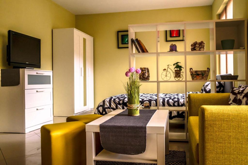 - un salon avec des chaises jaunes et une table fleurie dans l'établissement Semiramida Central Studio, à Varna